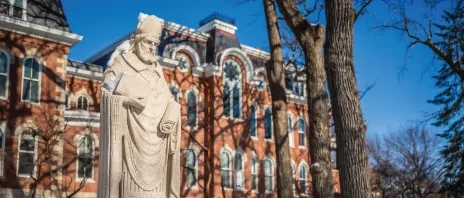 A stone statue of Saint 竞技宝app下载安装 of Milan outside in the snow.