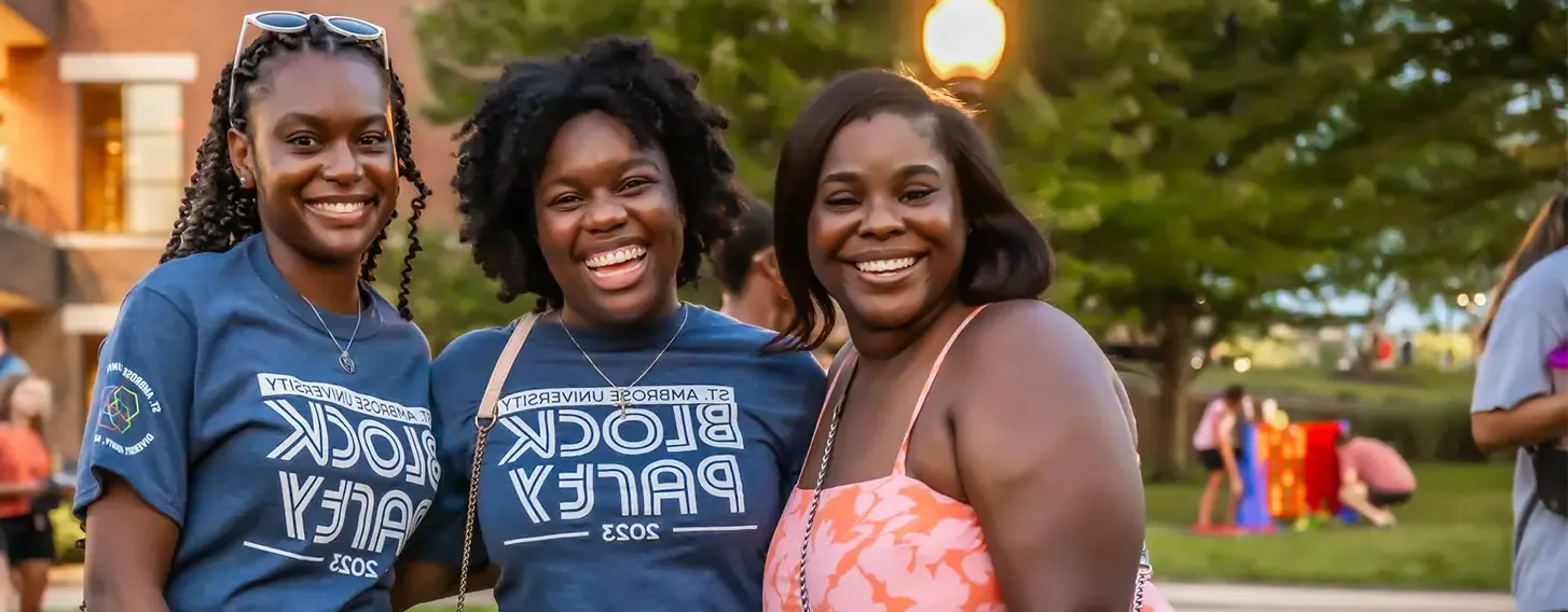 Three women smiling at a student block party.